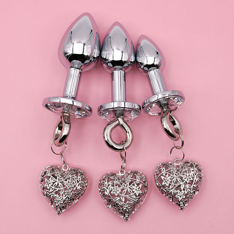 Metallic plug set with heart-shaped charms on pink background
